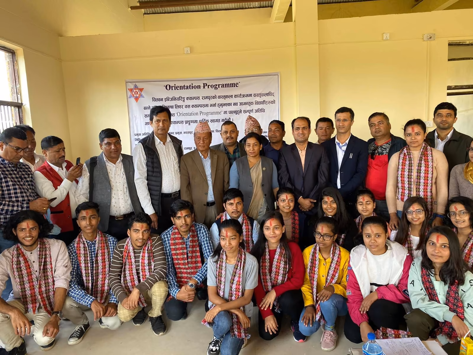 New students and staff in khada scarves at an orientation programme, its banner behind