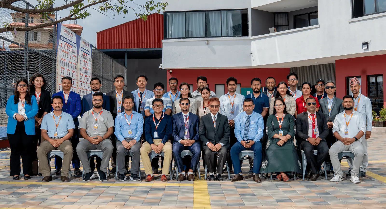 About forty staff and students seated and standing for a group photograph outside the college building