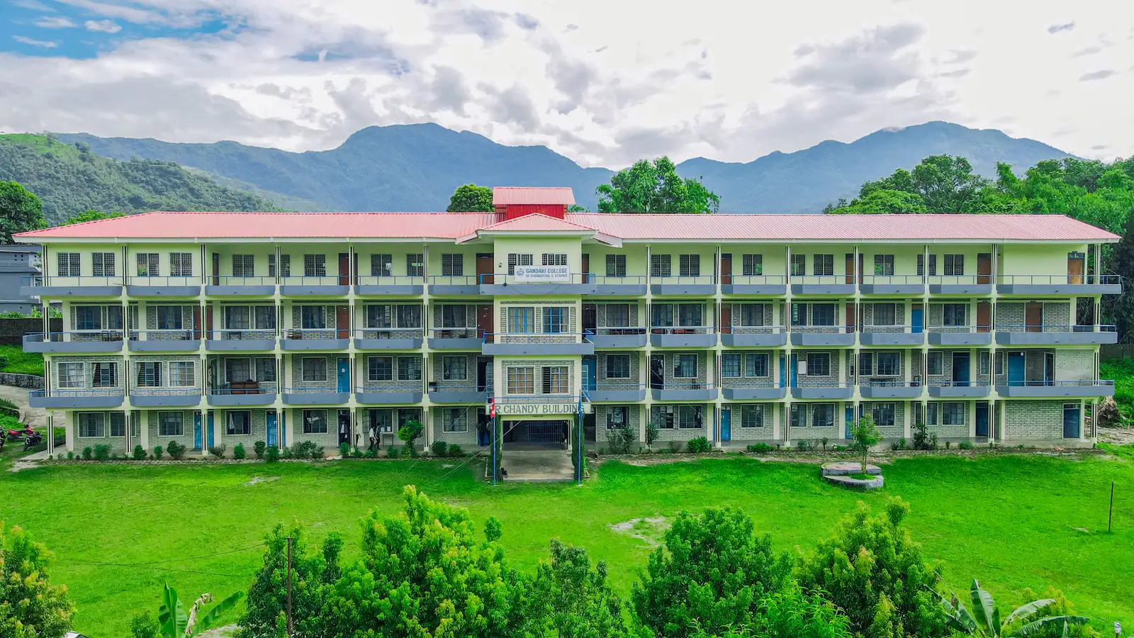 The college's long four-storey block above its lawn, green hills rising behind the roofline