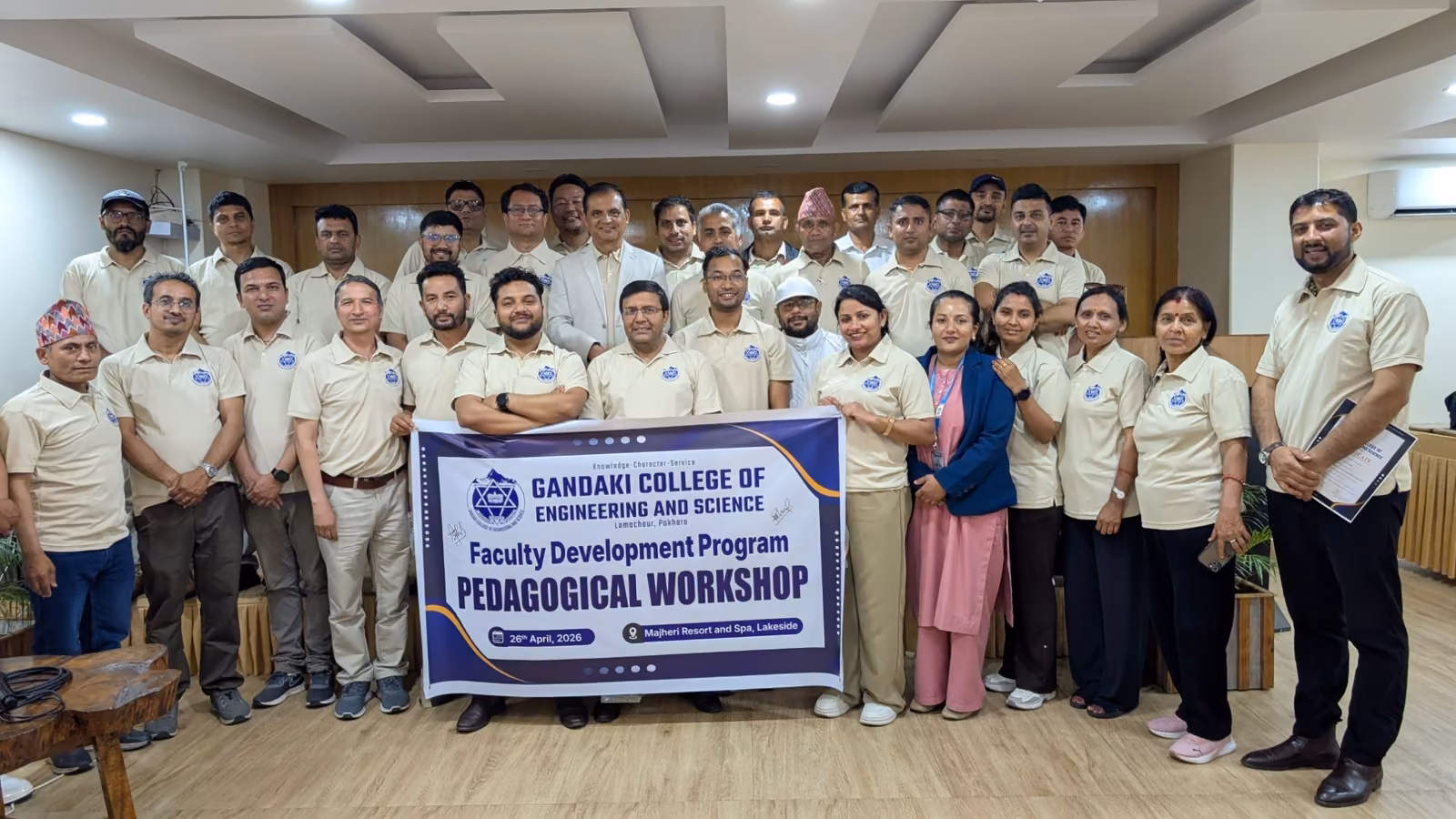 Participants of a faculty development workshop holding its banner in a hall