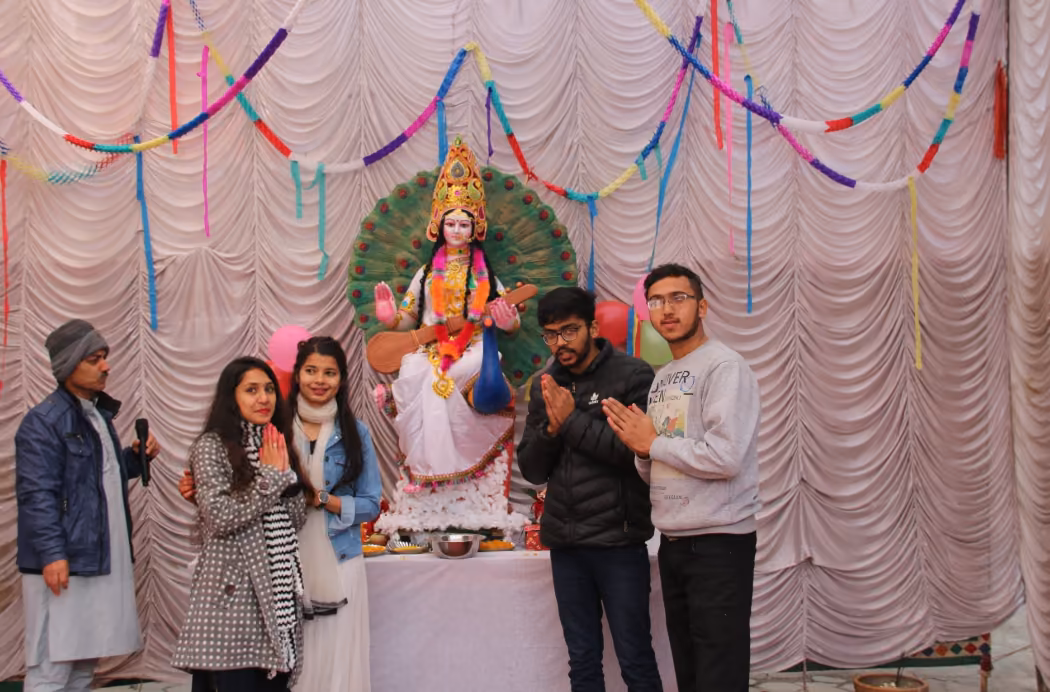 Students at a Saraswati shrine set up under draped curtains and paper streamers