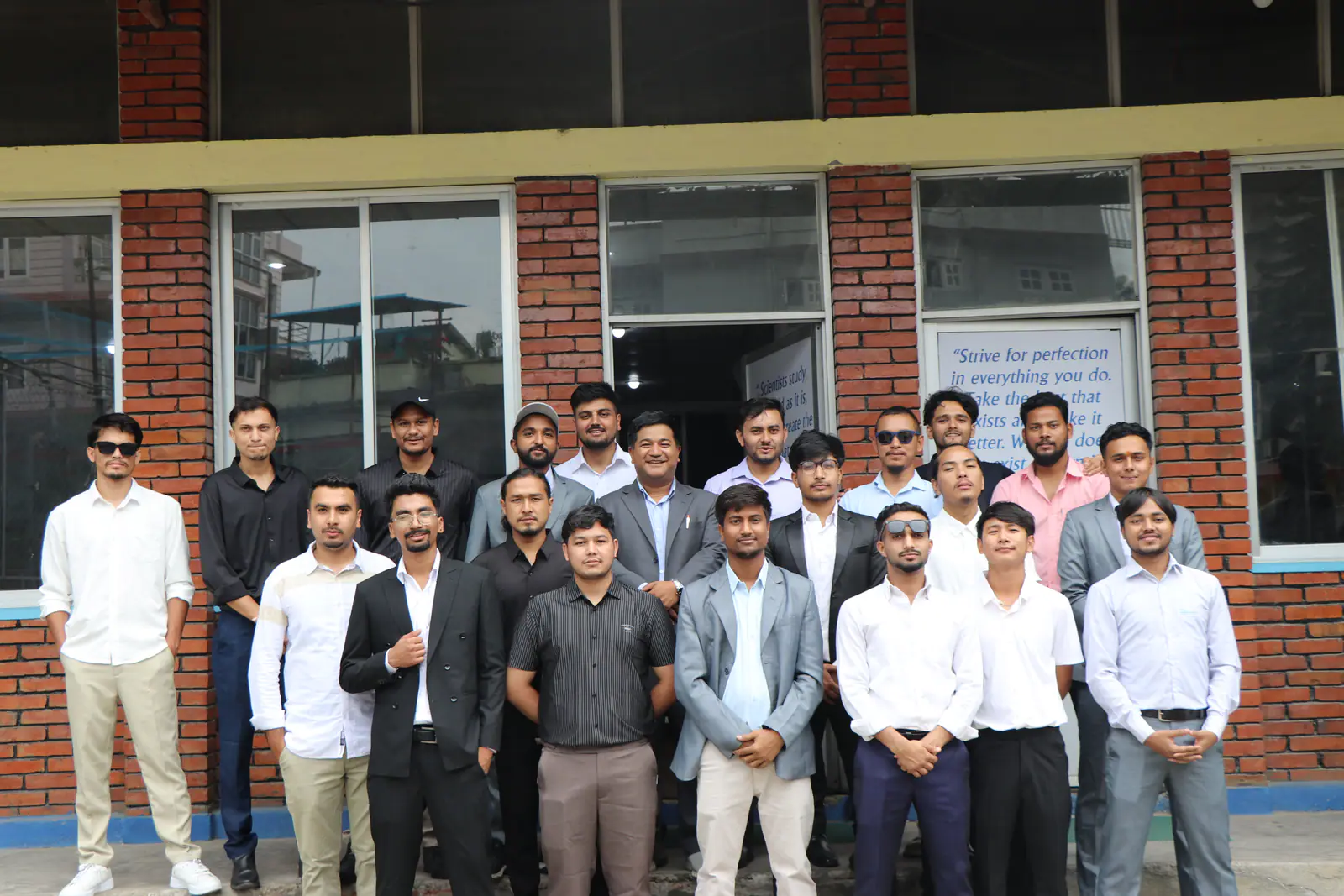 About twenty students outside the college block, its motto lettered on the window glass behind