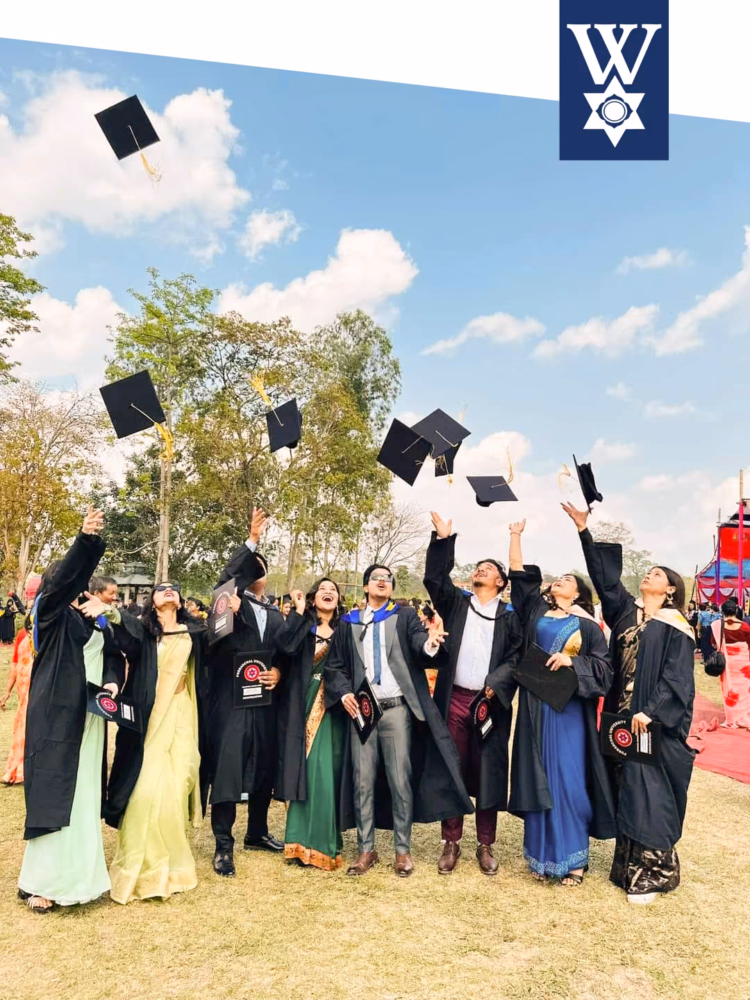 Graduates in gowns throwing their caps into the air outside the college