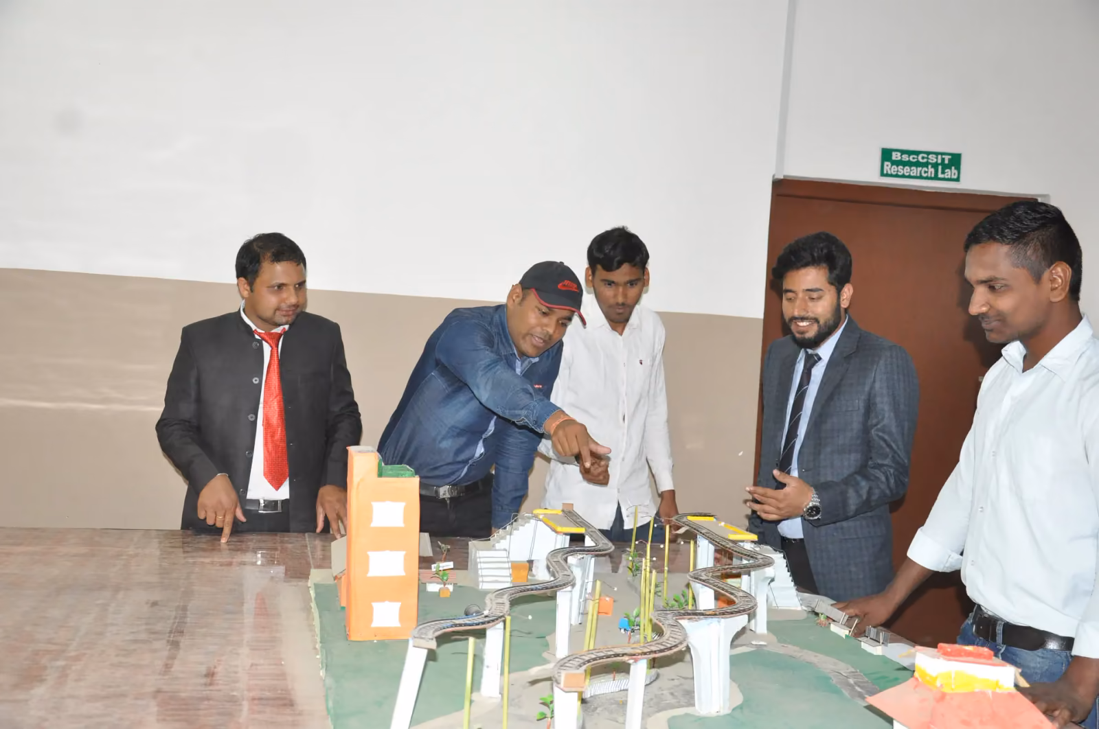 Staff and students round a table model of a road and buildings in the research lab