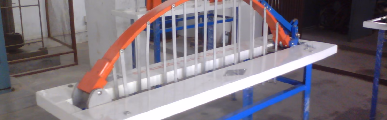 A model arch bridge clamped to a blue test frame in the laboratory