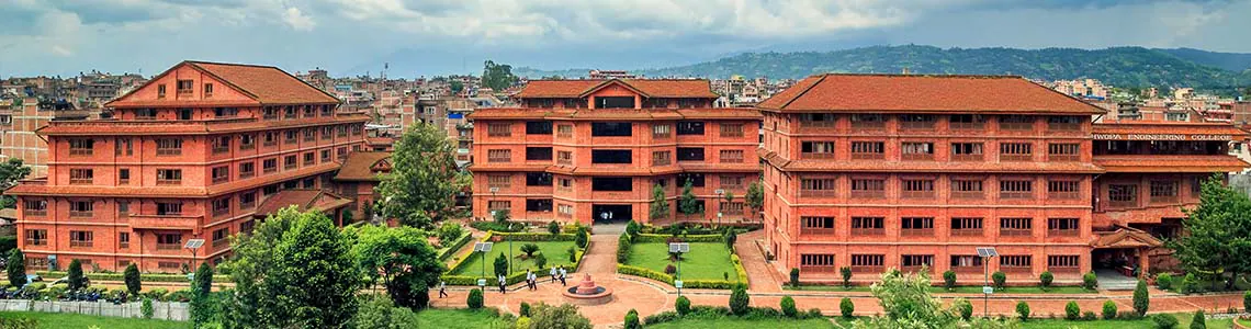 The college's red-brick complex from above, three long blocks around lawns with the valley behind