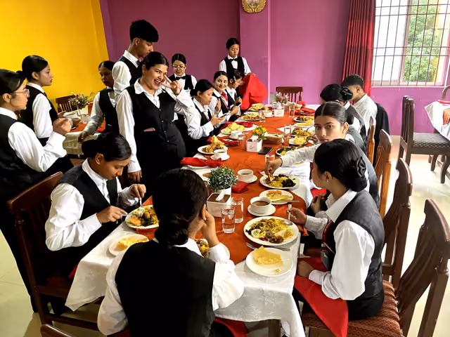 Students eating together at a long laid table in the training restaurant