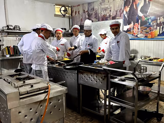 Students in chef's whites cooking at the range in the training kitchen