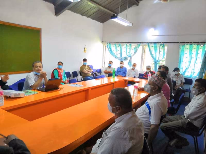 Participants round a long orange conference table in a decorated room