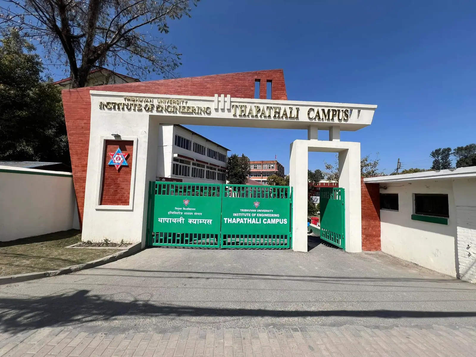 The campus gate under its signboard, the green metal leaves shut across the drive